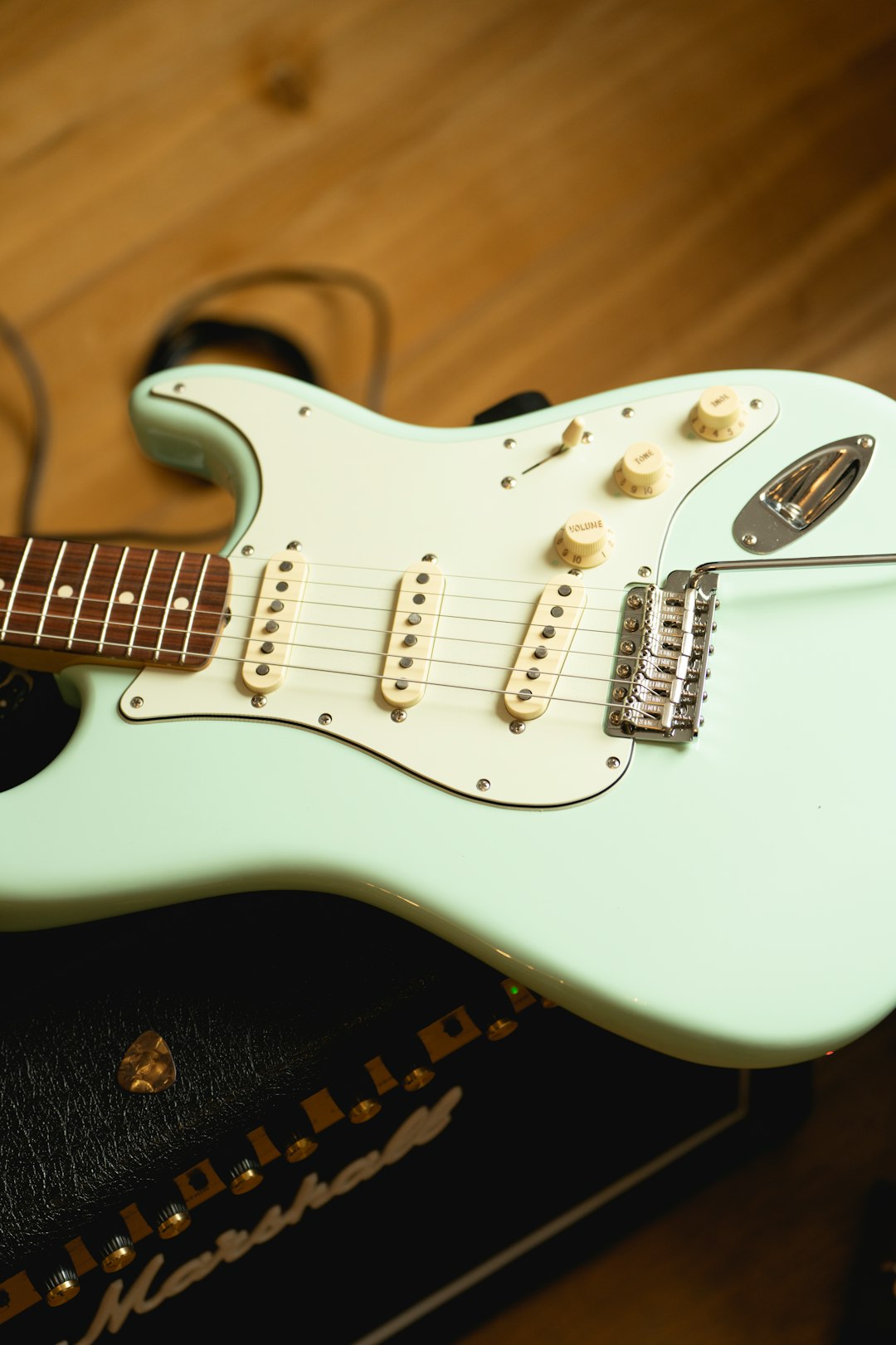 a-white-electric-guitar-sitting-on-top-of-a-wooden-floor-0vb8uojt5na